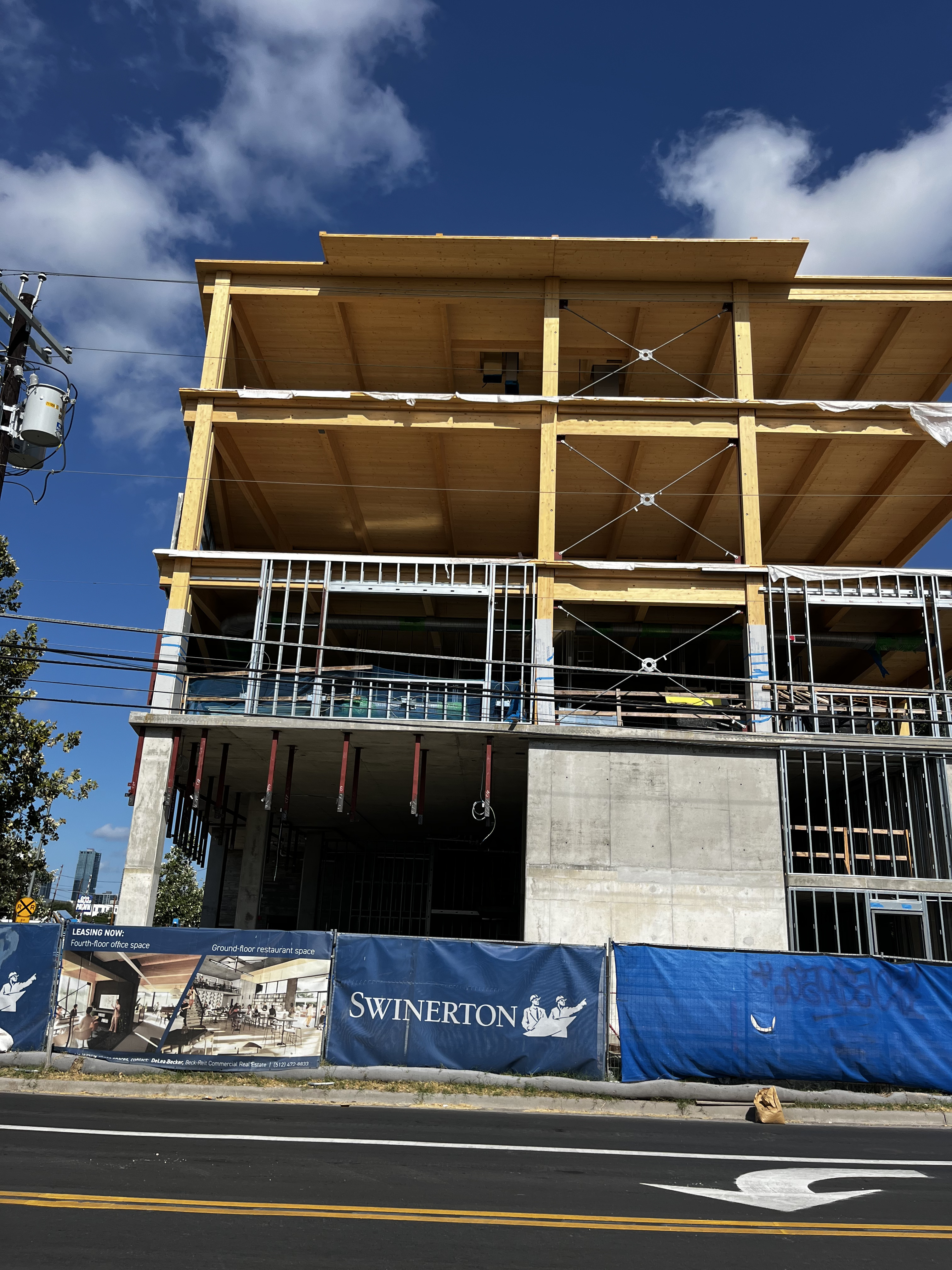 Mass timber building under construction, concrete base visible.