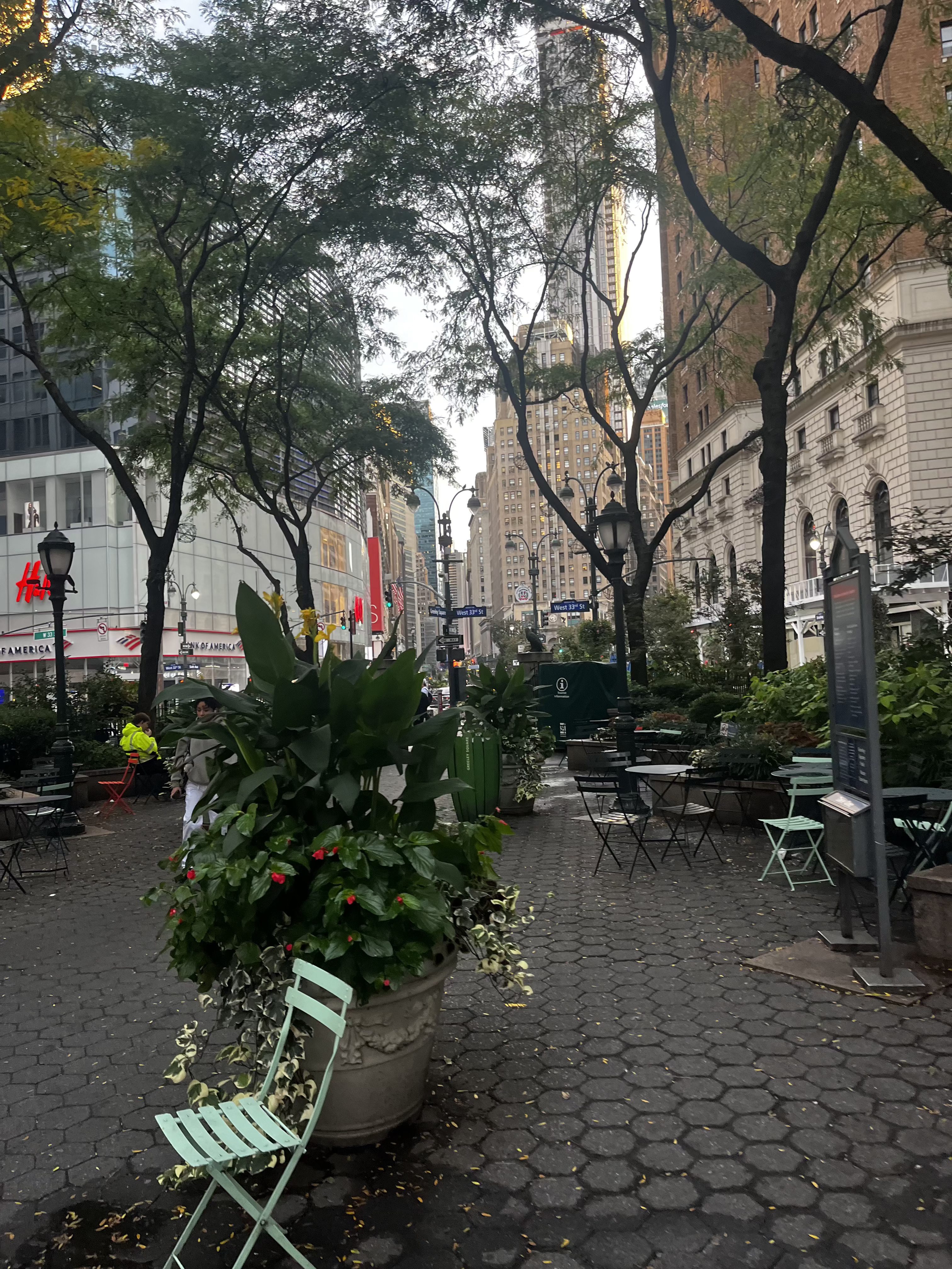 Urban park, quiet seating, greenery, and city backdrop.