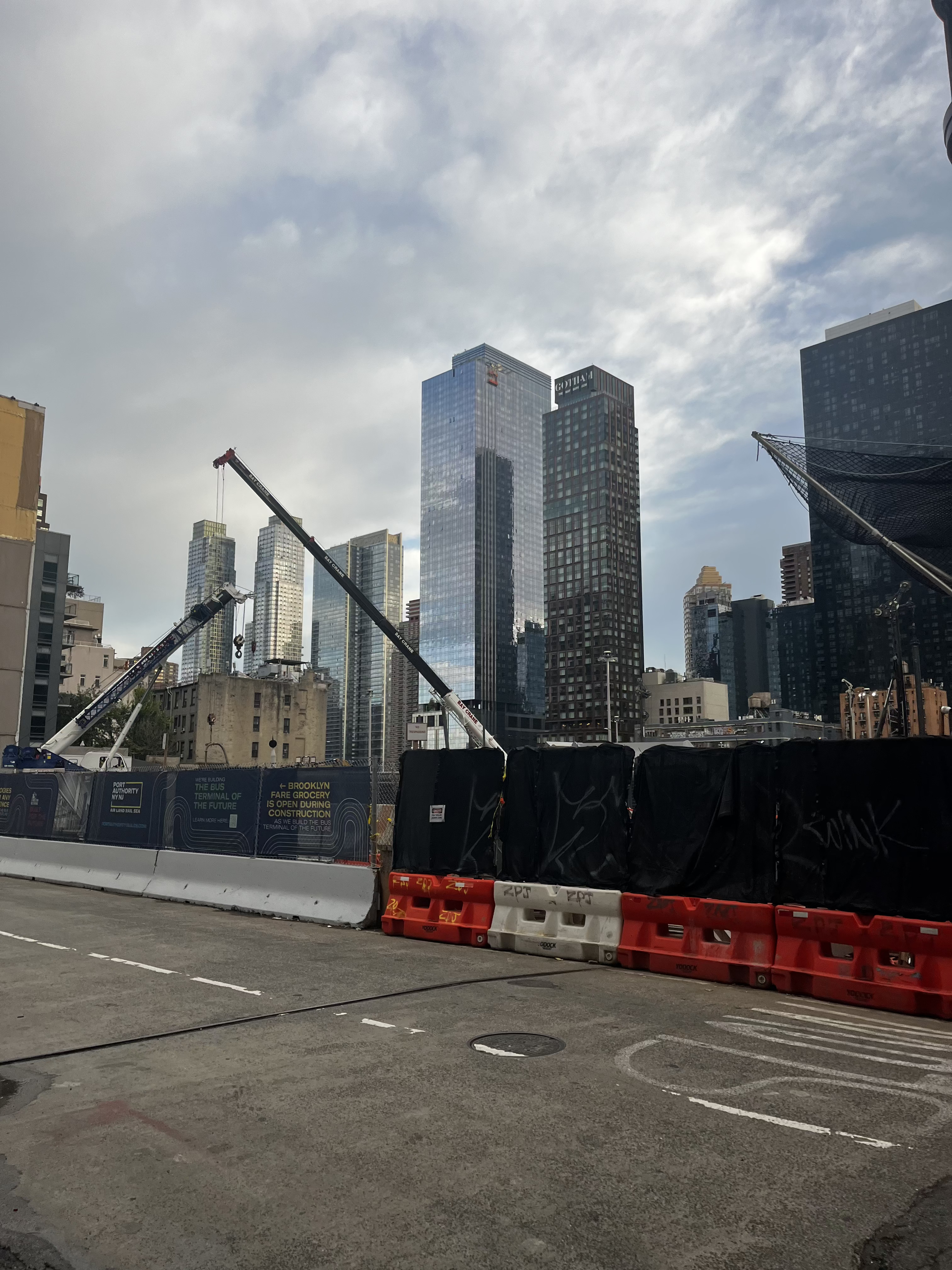 Construction zone shields city skyline, cranes dominate above.