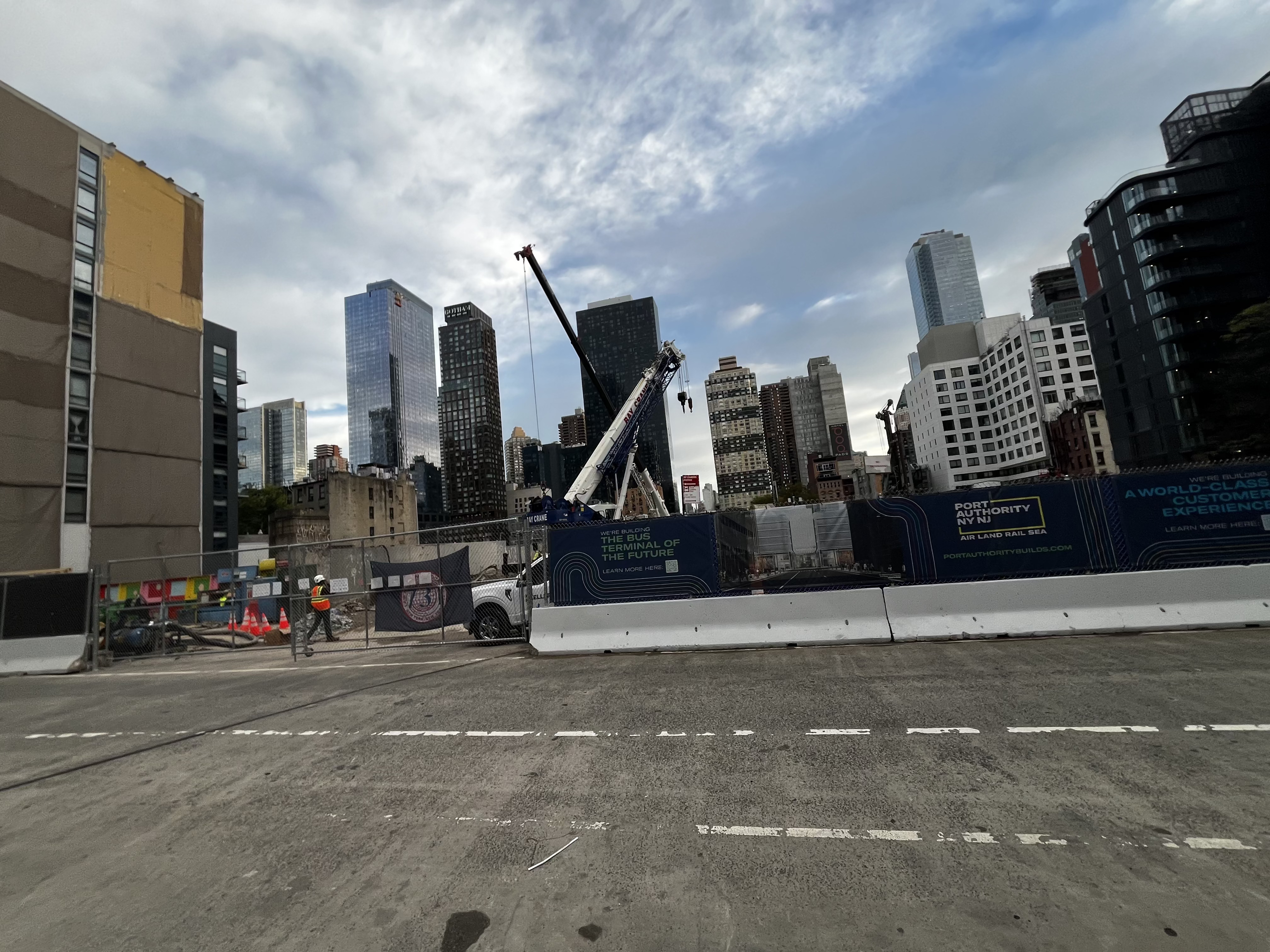 Construction site with city skyline under cloudy skies.